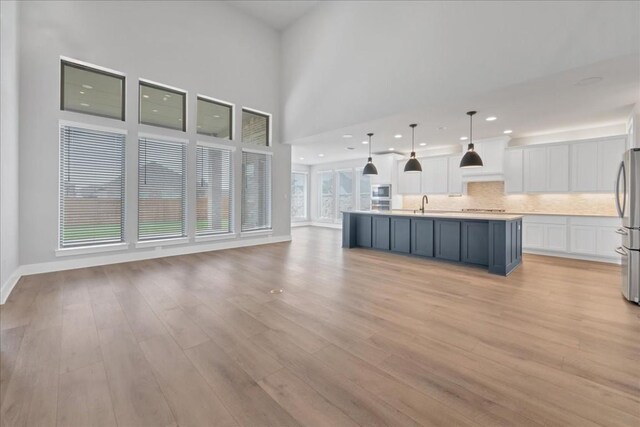 1400 Mulberry Oak Ln, Georgetown, TX 78628 - unfurnished living room featuring light wood-type flooring, a sink, a high ceiling, and baseboards