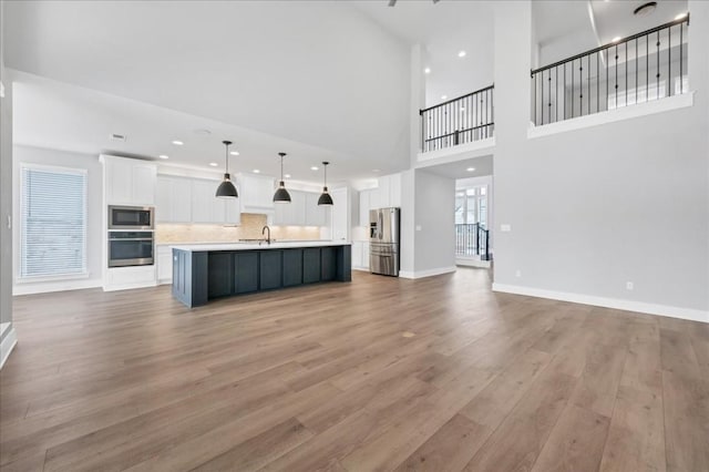 1400 Mulberry Oak Ln, Georgetown, TX 78628 - unfurnished living room with light wood-type flooring, a sink, baseboards, a high ceiling, and recessed lighting