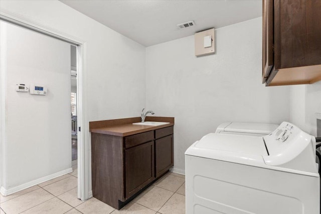 laundry area with visible vents, washing machine and dryer, a sink, cabinet space, and light tile patterned floors