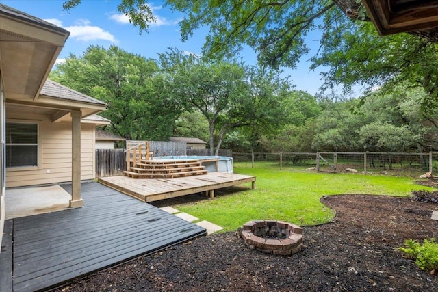 view of yard with a fenced backyard, a wooden deck, and an outdoor fire pit