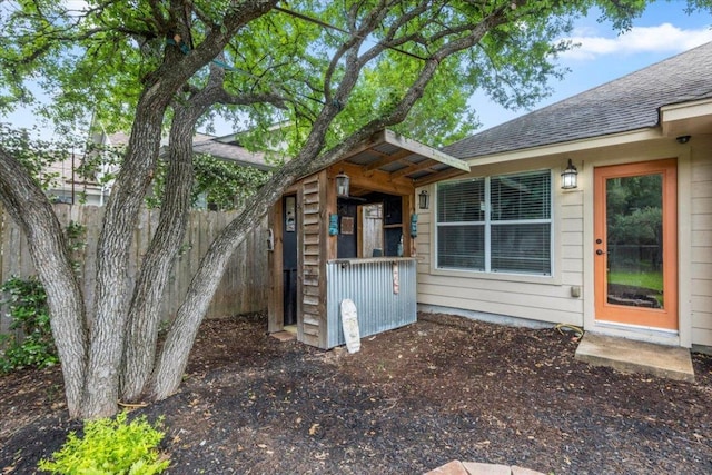 view of side of property with roof with shingles and fence
