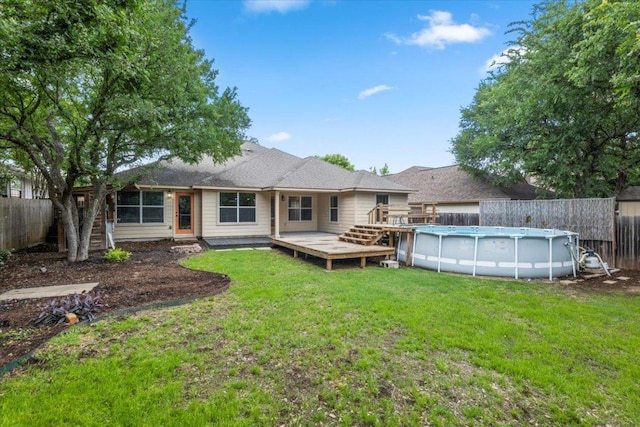 rear view of property with a fenced backyard, a fenced in pool, a yard, and a deck