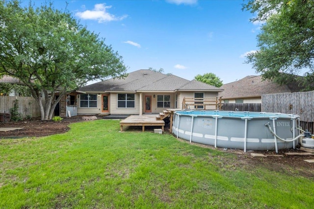 back of property featuring a yard, a fenced in pool, a wooden deck, and a fenced backyard