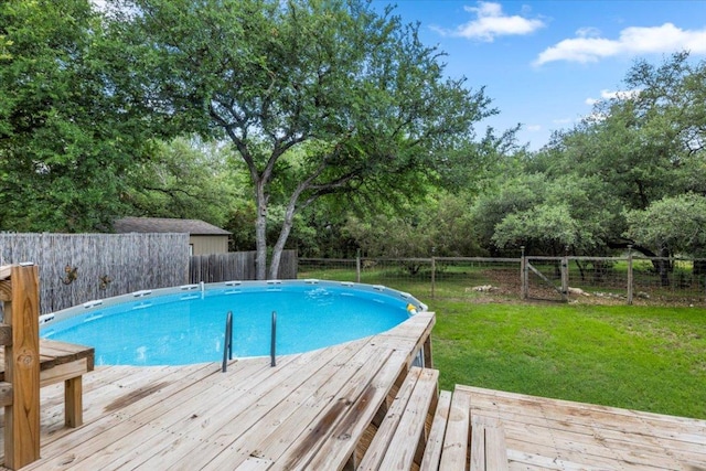 view of pool featuring a lawn, a fenced backyard, a wooden deck, and a fenced in pool