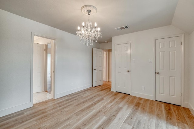15203 Dormax Cir, Leander, TX 78641 - unfurnished bedroom with a chandelier, light wood-style flooring, baseboards, and connected bathroom