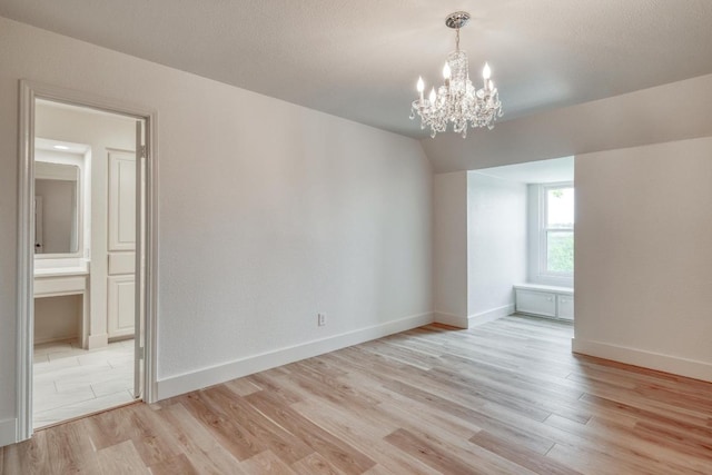 15203 Dormax Cir, Leander, TX 78641 - spare room with a chandelier, light wood-style flooring, baseboards, and lofted ceiling