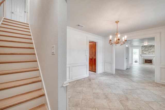 15203 Dormax Cir, Leander, TX 78641 - stairs with a decorative wall, a chandelier, ornamental molding, and a fireplace