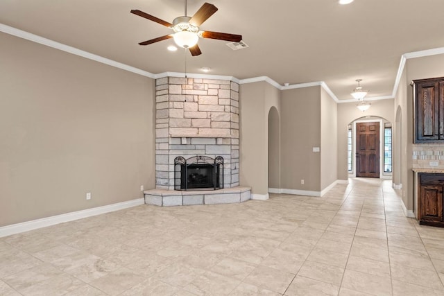 unfurnished living room with a ceiling fan, a stone fireplace, visible vents, arched walkways, and ornamental molding