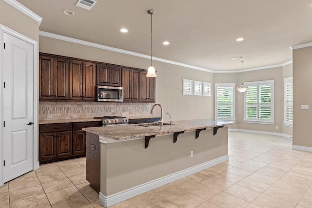 kitchen featuring appliances with stainless steel finishes, a breakfast bar, a sink, tasteful backsplash, and visible vents