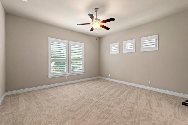 carpeted spare room with baseboards and a ceiling fan