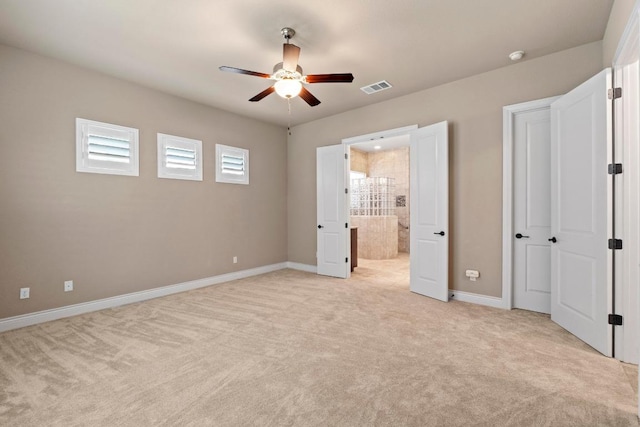unfurnished bedroom featuring baseboards, light colored carpet, ensuite bath, and visible vents