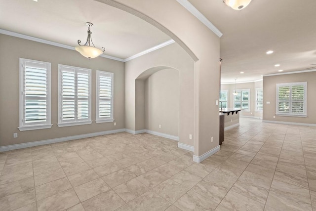 spare room featuring recessed lighting, ornamental molding, baseboards, and arched walkways