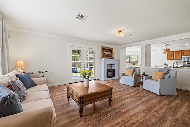 living area featuring plenty of natural light, ornamental molding, and visible vents