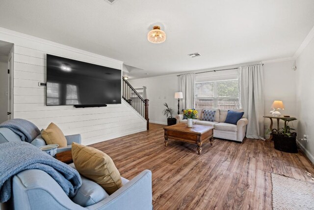 living room with crown molding, baseboards, stairs, and wood finished floors