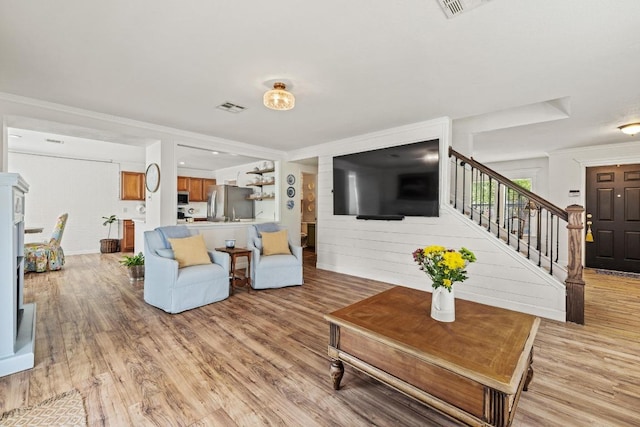 living room featuring stairs, visible vents, and light wood finished floors