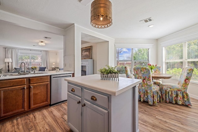 kitchen with a sink, light wood-style floors, light countertops, stainless steel dishwasher, and visible vents