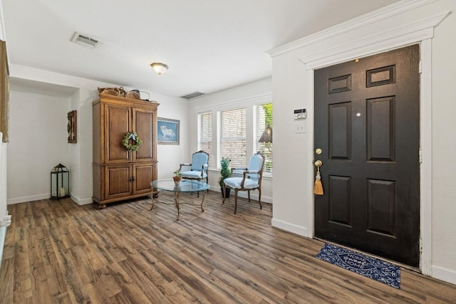 foyer featuring baseboards, wood finished floors, and visible vents