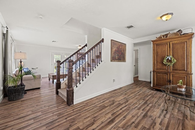 foyer featuring visible vents, crown molding, stairway, baseboards, and dark wood-type flooring