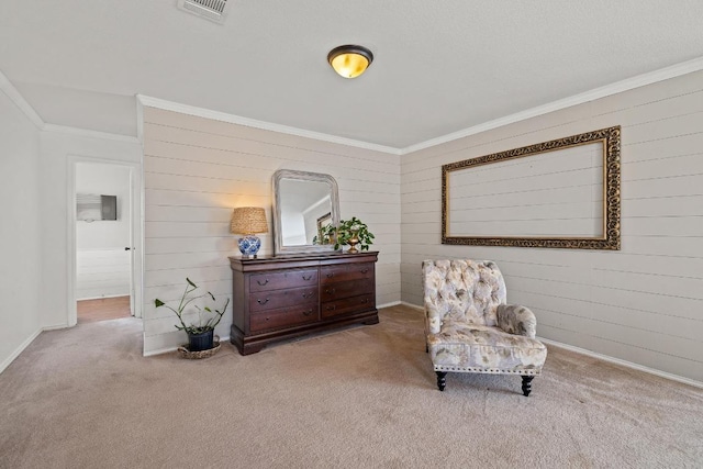 living area with visible vents, crown molding, wood walls, baseboards, and carpet flooring