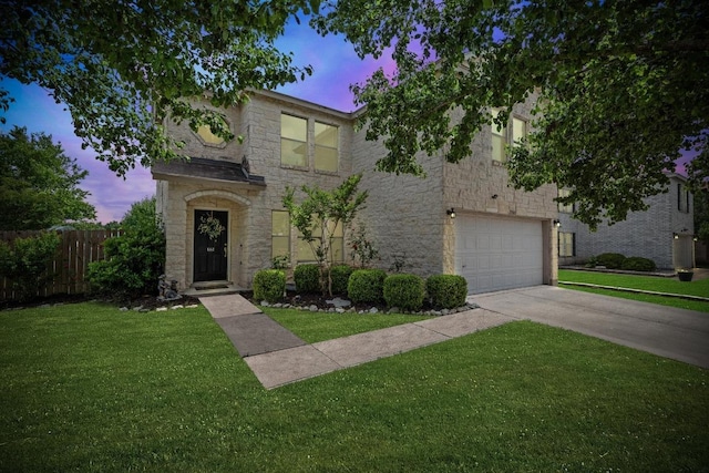 traditional home featuring fence, a lawn, driveway, and stone siding