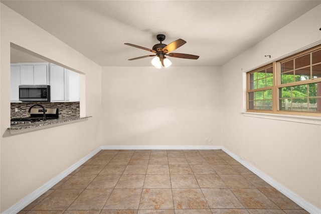 interior space featuring baseboards, ceiling fan, and light tile patterned floors