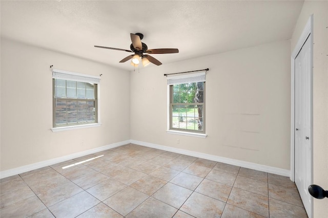unfurnished room featuring baseboards, ceiling fan, and light tile patterned floors