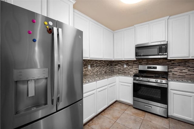 kitchen with white cabinets, appliances with stainless steel finishes, decorative backsplash, and light tile patterned floors