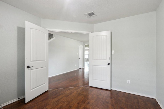 unfurnished room with baseboards, wood finished floors, and visible vents