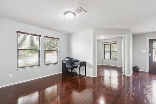 interior space featuring baseboards, a textured ceiling, wood finished floors, and visible vents