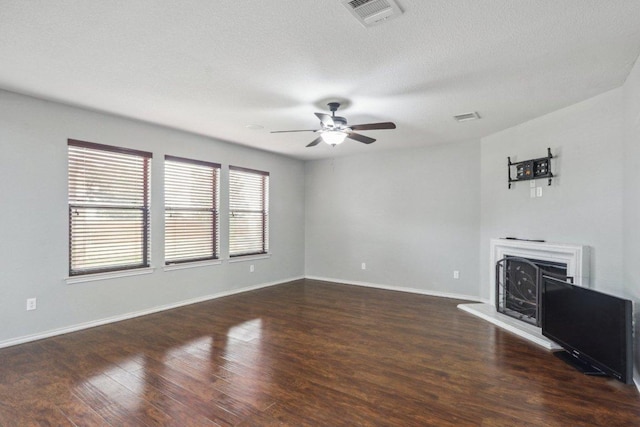 unfurnished living room featuring visible vents, a fireplace with raised hearth, ceiling fan, and wood finished floors
