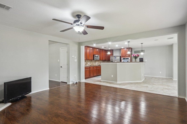 unfurnished living room with a ceiling fan, baseboards, visible vents, and light wood-style flooring
