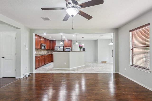 unfurnished living room featuring baseboards, ceiling fan, light wood-type flooring, and visible vents