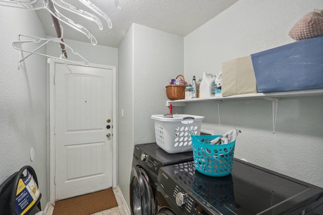 clothes washing area featuring laundry area, washer and clothes dryer, and a textured wall