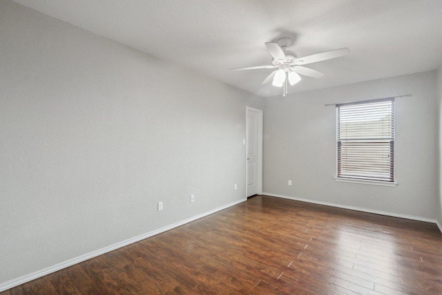 empty room with dark wood-style flooring, baseboards, and a ceiling fan