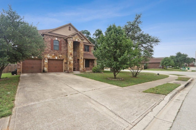 traditional home featuring an attached garage, concrete driveway, stone siding, and a front yard