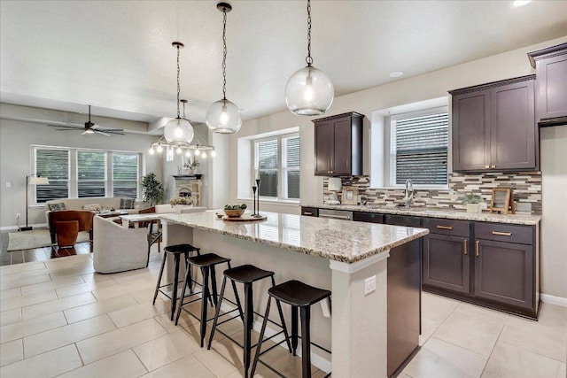 kitchen with decorative backsplash, a kitchen island, open floor plan, a kitchen breakfast bar, and light stone counters
