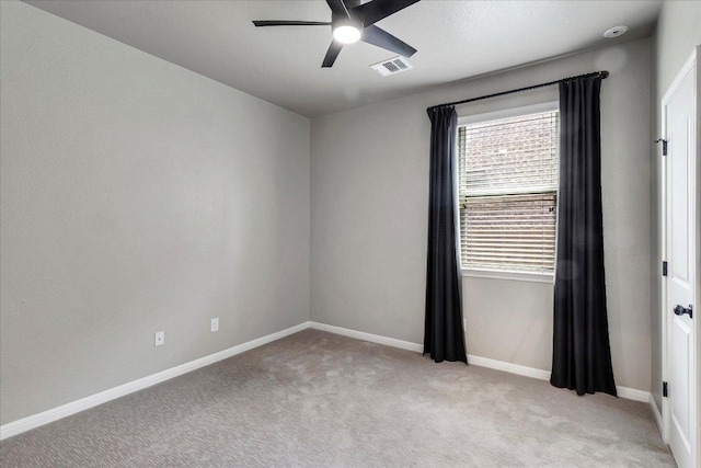 empty room with ceiling fan, visible vents, light carpet, and baseboards