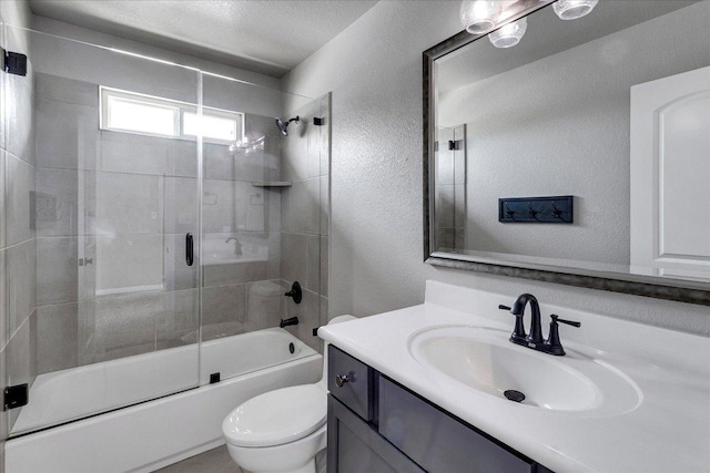 bathroom with vanity, a textured wall, enclosed tub / shower combo, and toilet
