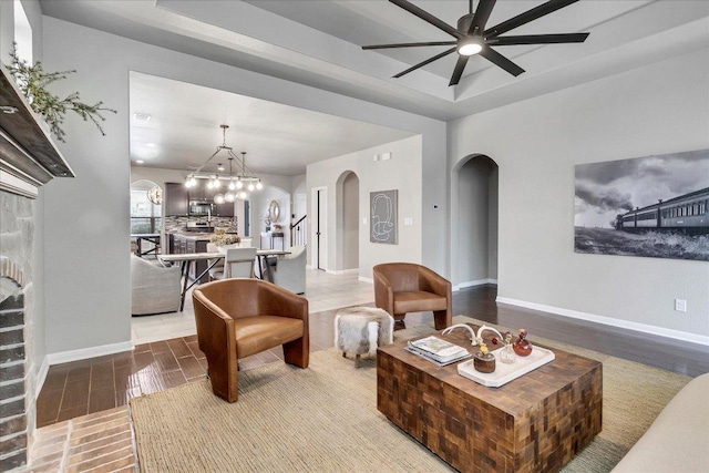 5684 Sabbia Dr, Round Rock, TX 78665 - living area featuring arched walkways, a ceiling fan, wood finished floors, a chandelier, and a tray ceiling