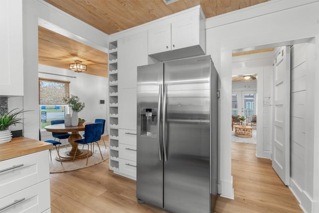 1802 Webberville Rd, Austin, TX 78721 - kitchen featuring white cabinets, wooden ceiling, light wood-style flooring, and stainless steel fridge with ice dispenser