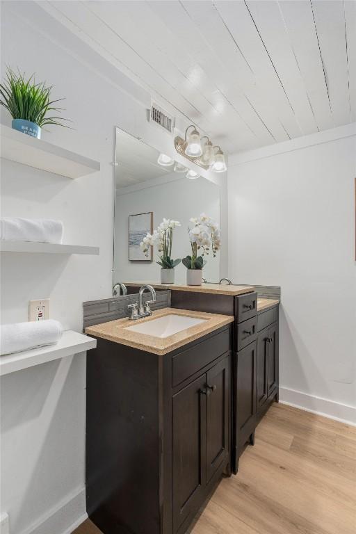 1802 Webberville Rd, Austin, TX 78721 - bathroom featuring baseboards, visible vents, wood finished floors, and vanity