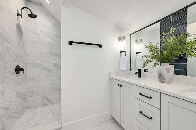 bathroom with double vanity, baseboards, a tile shower, and marble finish floor