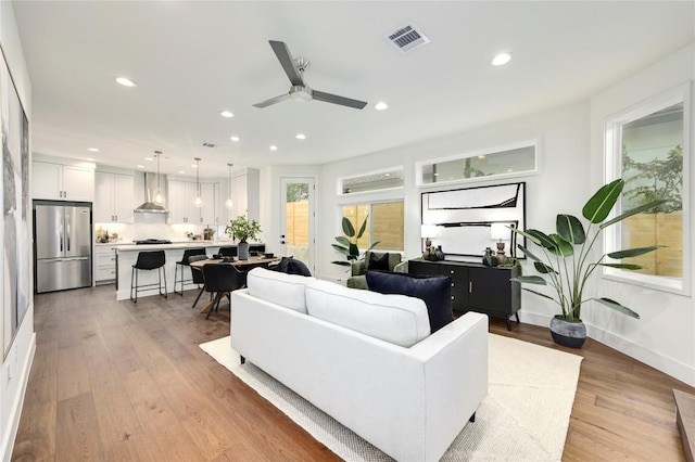 living area with visible vents, baseboards, recessed lighting, light wood-type flooring, and a ceiling fan