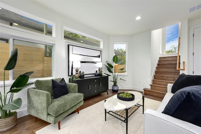 living room featuring visible vents, stairs, wood finished floors, and a wealth of natural light