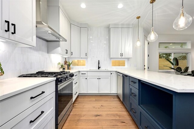 1806 Maple Ave Unit 1, Austin, TX 78702 - kitchen featuring stainless steel appliances, wall chimney range hood, a sink, white cabinetry, and a peninsula