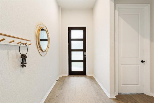 doorway with baseboards and light wood-style flooring