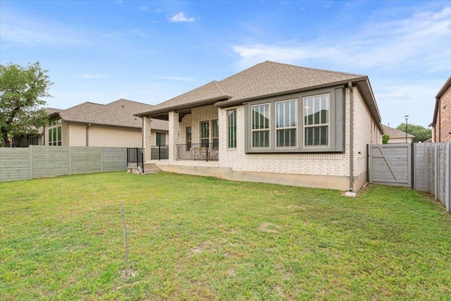 rear view of house with a lawn, brick siding, and a fenced backyard