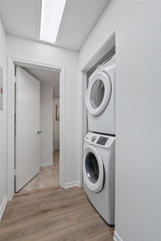 1601 Faro Dr Unit 1102, Austin, TX 78741 - washroom with baseboards, stacked washer and clothes dryer, wood finished floors, and laundry area