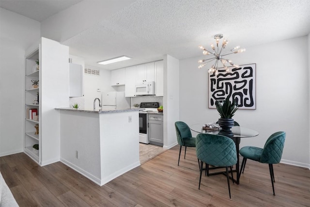 1601 Faro Dr Unit 1102, Austin, TX 78741 - kitchen featuring an inviting chandelier, a textured ceiling, wood finished floors, and white appliances