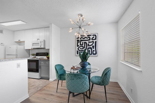 1601 Faro Dr Unit 1102, Austin, TX 78741 - dining space with a textured ceiling, a chandelier, light wood-style flooring, baseboards, and visible vents